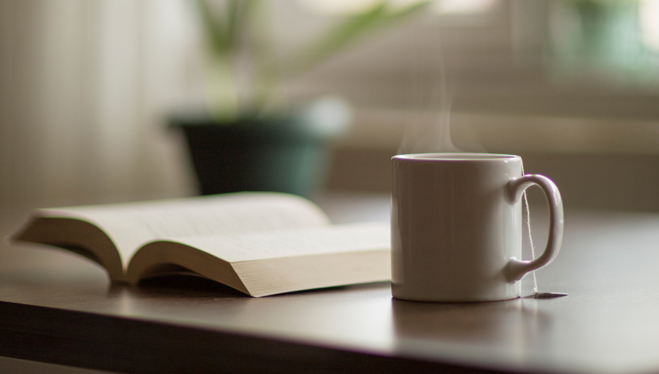 Imagem de tempo frio, com um livro e uma caneca de chá. Créditos: Canva