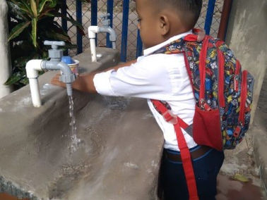 Ein kleiner Junge wäscht sich die Hände am neuen Brunnen