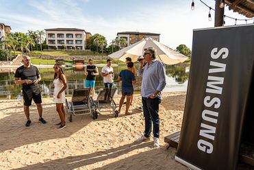 Grupo de personas en un evento junto a un lago, con cartel Samsung.