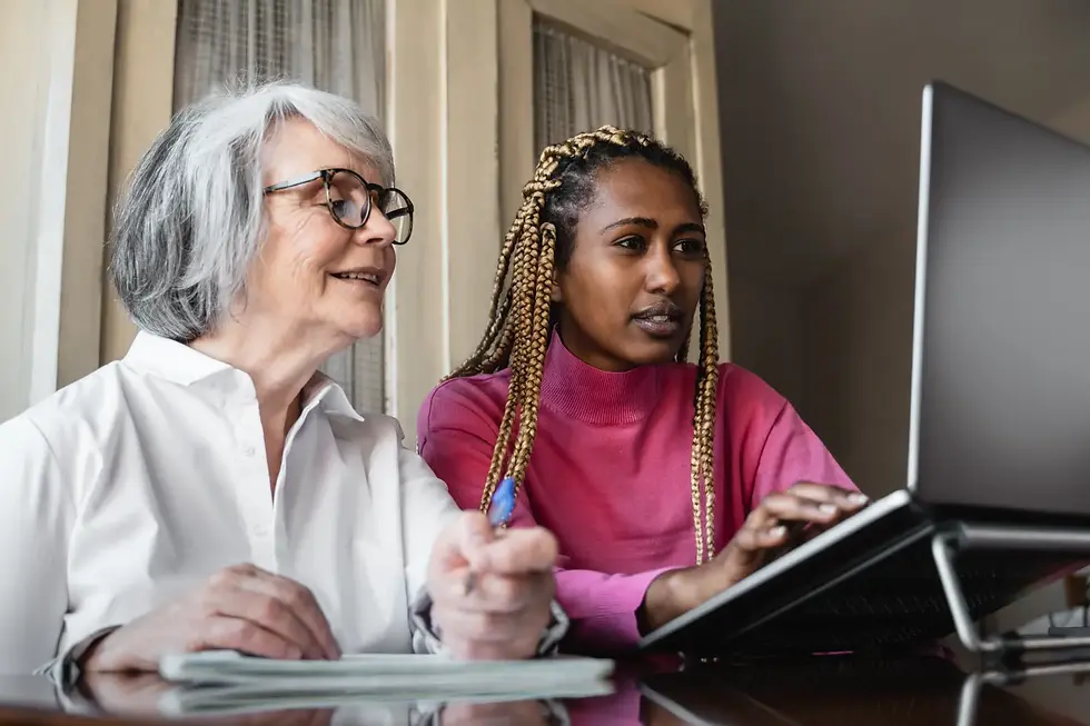 A younger woman supporting an older woman with paperwork and a laptop, reflecting how assessors assist clients in understanding legal processes and giving instructions