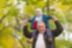 Smiling grandfather carrying his young grandchild on his shoulders, showing positive outcomes after capacity assessments for property transactions.