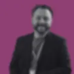 Smiling professional portrait of Ben from Nellie Supports, with a purple branded background.