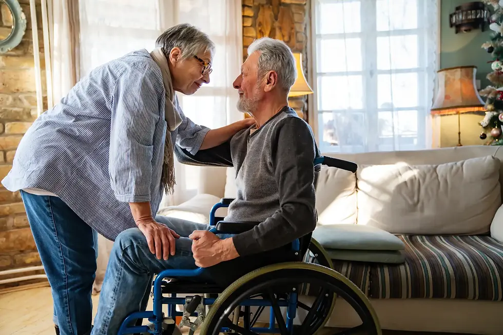 Elderly man in a wheelchair supported by his partner at home, highlighting the importance of residency capacity decisions for safety and wellbeing