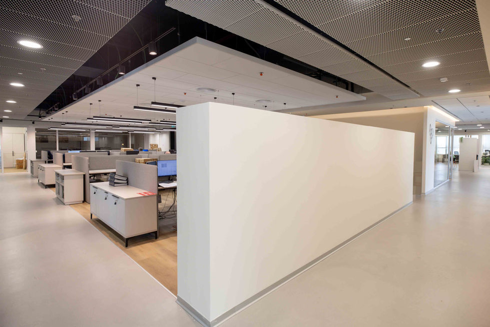 חלל עבודה פתוח (Open Space) במשרדי חברת ברן, לצד מחיצת קיר לבנה ומינימליסטית.