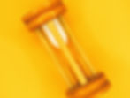 Wooden hourglass with white sand on a vibrant yellow background