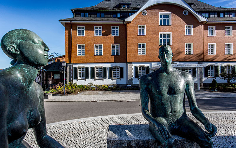 Zwei Skulpturen sitzender Menschen vor der Fachklinik St. Georg.