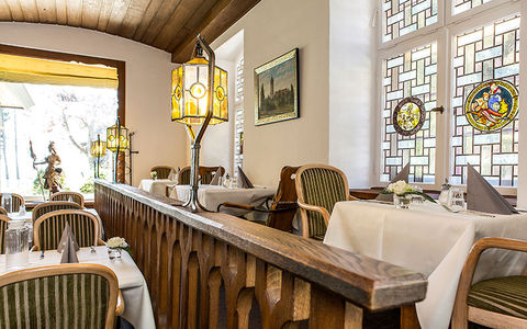 Traditionell eingerichteter Speisesaal mit Holzmöbeln, weißen Tischdecken und Kronleuchter.