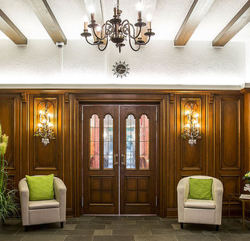 Eingangsbereich im historischen Stil mit Holzwänden, Sesseln und gedämpfter Beleuchtung.