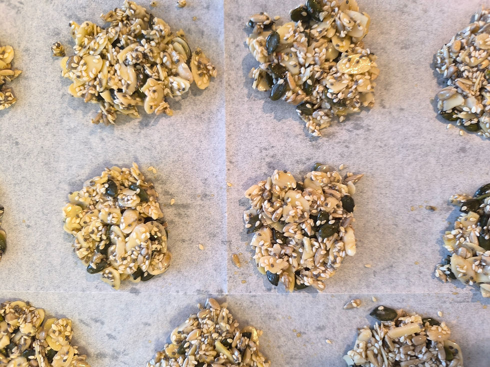 Clusters of mixed seeds and nuts on parchment paper, arranged in rows. Warm tones and a rustic texture create a natural, homemade feel.