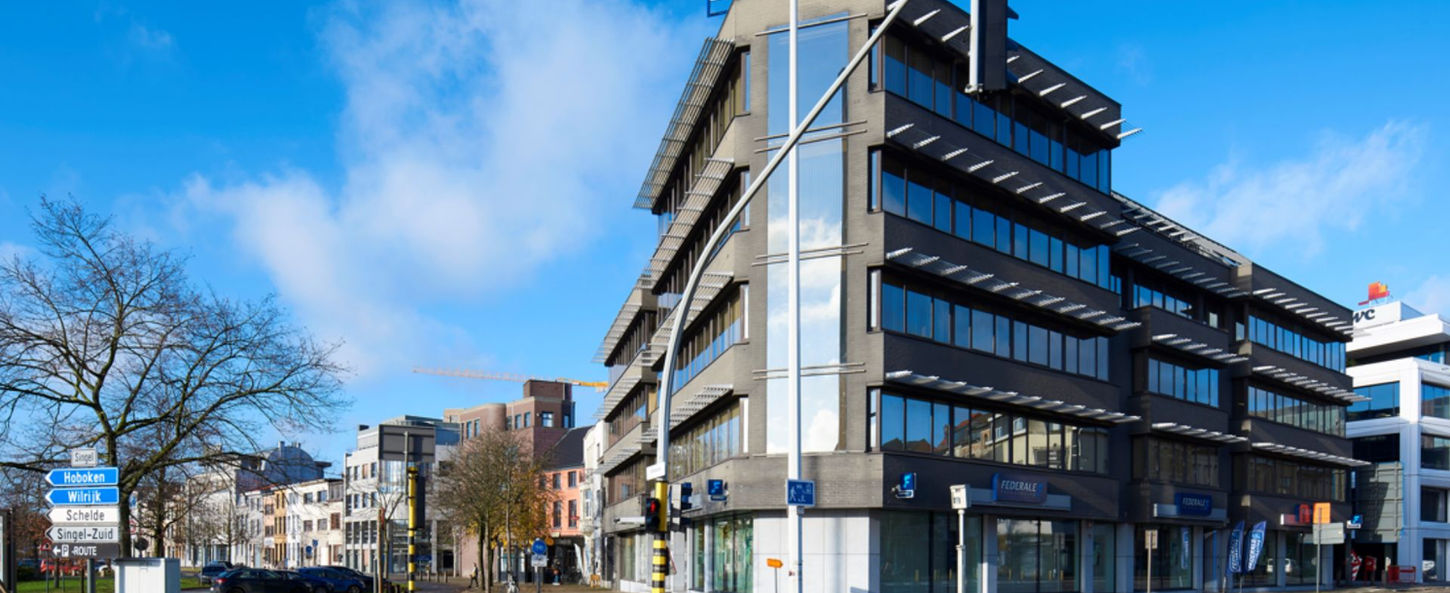 Immeuble de bureaux Carlton Building à Anvers, avec des espaces de travail modernes et des parkings disponibles.