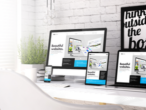 Modern responsive website design displayed on desktop computer, laptop, tablet, and smartphone on a clean office desk.