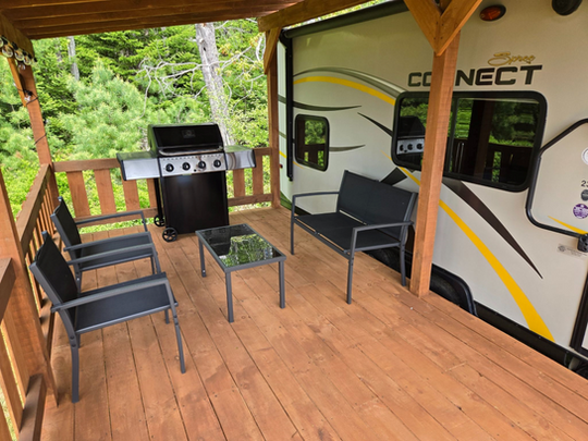 Outdoor deck with grill and seating next to a Connect RV.