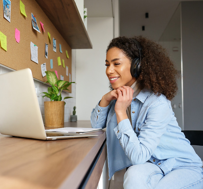 Smiling young african american teen girl wear headphones video calling on laptop Happy mix