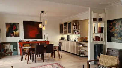 Rénovation d'un appartement haussmannien : transformation d'un double séjour sombre en un espace de vie contemporain avec parquet clair et luminaires design à filaments.