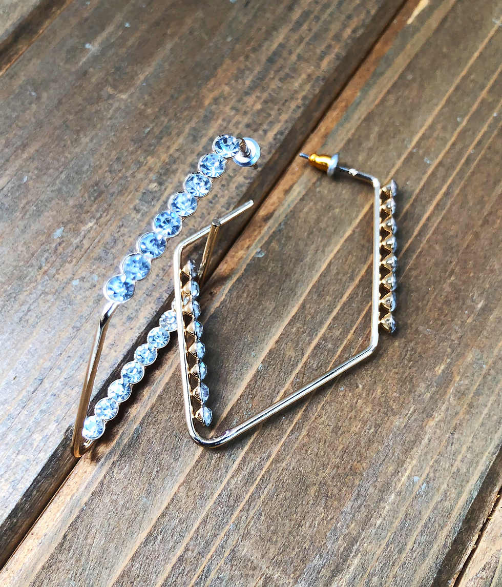 Elegant gold earrings with blue rhinestones on a wooden surface.