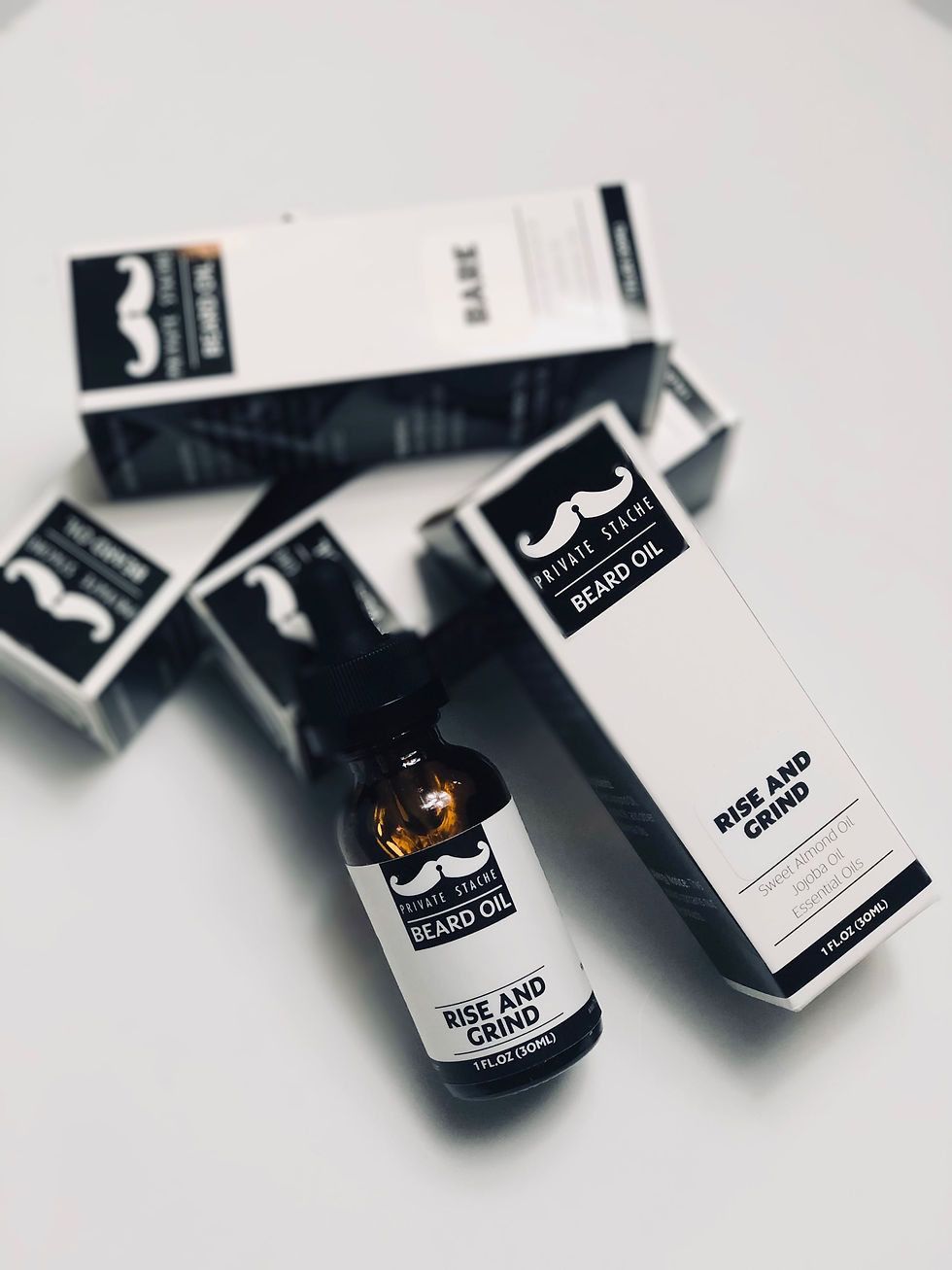 Thumbnail: Rise and Grind beard oil bottle and boxes with product branding on table