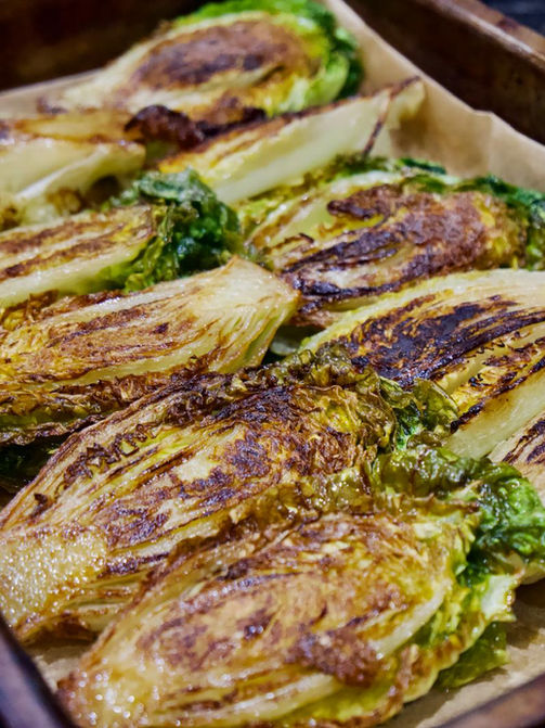 Grilled romaine lettuce wedges in a baking tray, ready to serve.