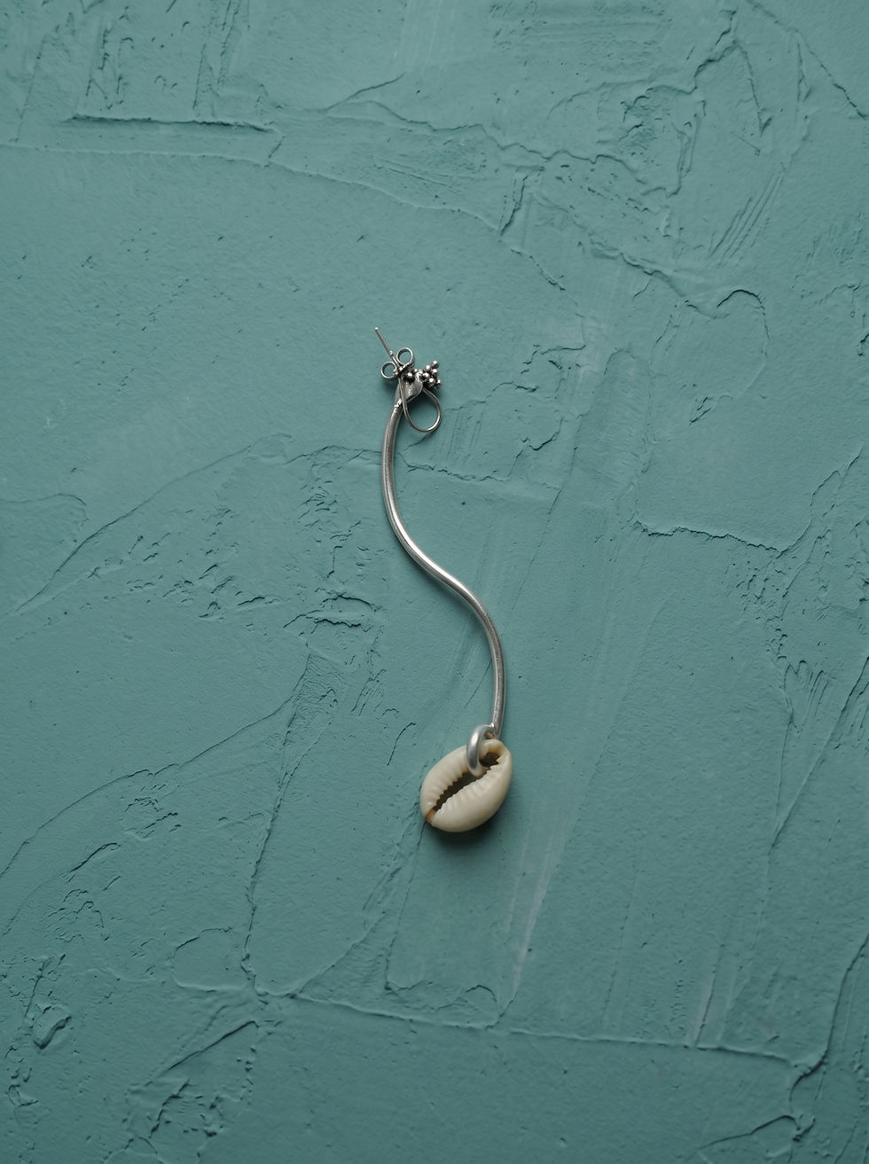 Cowrie shell drop earring with a silver S-curve wire by MHL Jewelry Designs.