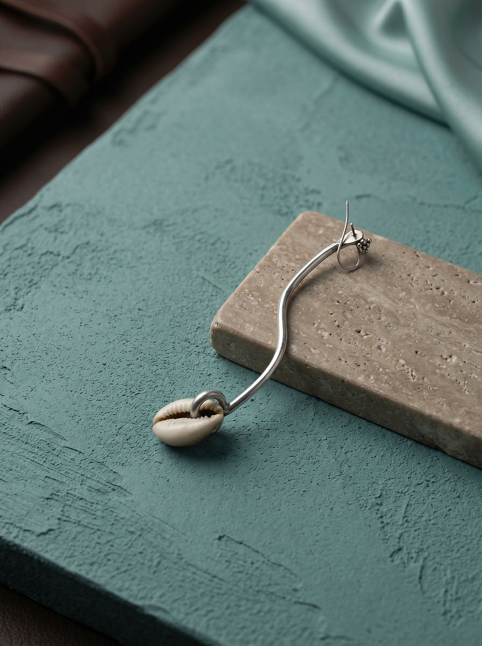 Cowrie shell drop earring with a silver S-curve wire by MHL Jewelry Designs.