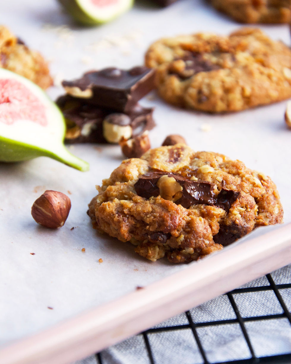 Side close up of Oatmeal cookies with chocolate chunks, hazelnuts and dried figs on cooling rack.
