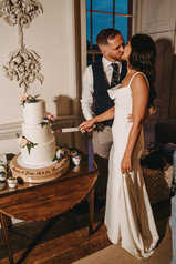 A bride and groom cut their wedding cake beside elegant interior details