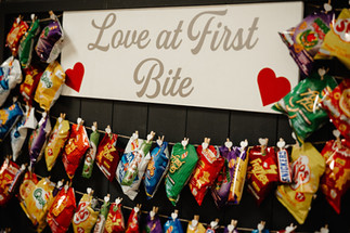 A colourful snack display titled “Love at First Bite” featuring crisps and sweets