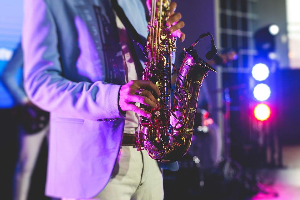 A saxophonist performs under colourful stage lighting during a lively evening set