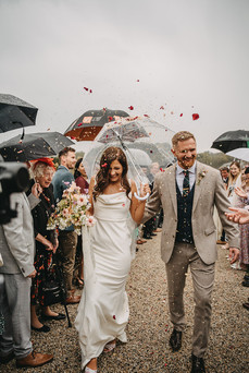 Newlyweds walk through confetti thrown by cheering guests outside the venue