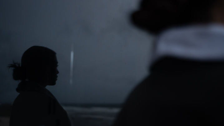 Silhouettes of two people facing a window over the sea at dusk at Maiim, Tulum.
