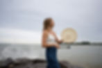 Toronto spiritual healer Liv Arcangeli playing a shamanic drum by the water