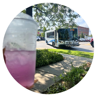 purple drink in the foreground and an ORT bus in the background in focus turning in downtown fayetteville