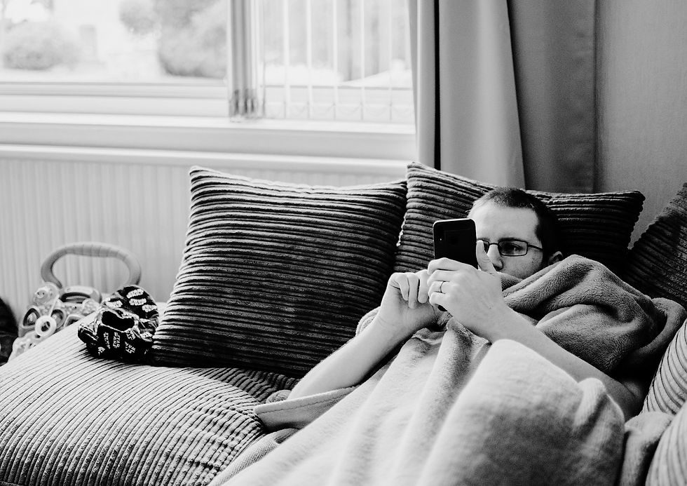 man on his phone in bed wearing glasses