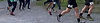 Runners with numbers visible are racing on a gravel path during event.