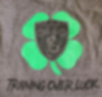Shamrock back design with MIBP logo in center words under design say training over luck
