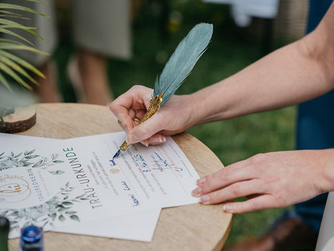 Braut unterschreibt mit einer Feder das Hochzeitsdokument – letzter Schritt vor dem großen Tag