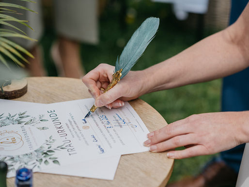 Braut unterschreibt mit einer Feder das Hochzeitsdokument – letzter Schritt vor dem großen Tag