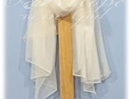 Una cruz de madera con un manto blanco descansando sobre ella.
