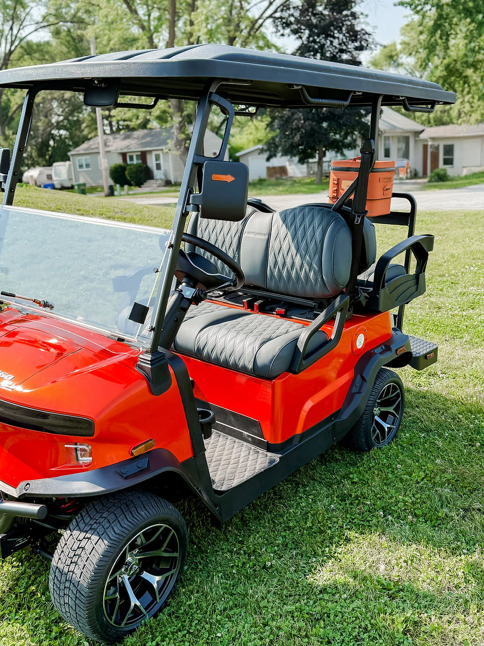 Thumbnail: Bright red Denago golf cart with black seats and an orange YETI Hopper Flip 12 cooler mounted using the Cooler Caddie.