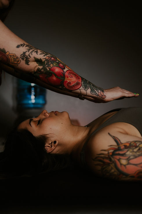 tattooed arms performing reiki over the heart chakra
