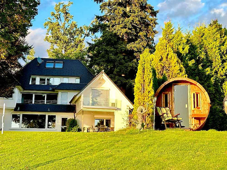 Frontale Ansicht der wunderschönen Villa Noho, ihres Gartens und auf der rechten Seite der Sauna in der Nähe des Strandes.