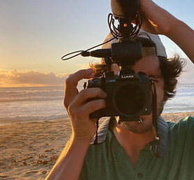 Photo of Pierre-Yves Beaulieu holding a camera on a beach, with a sunset in the background.