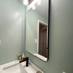 Vertical bathroom mirror above charcoal tile floors