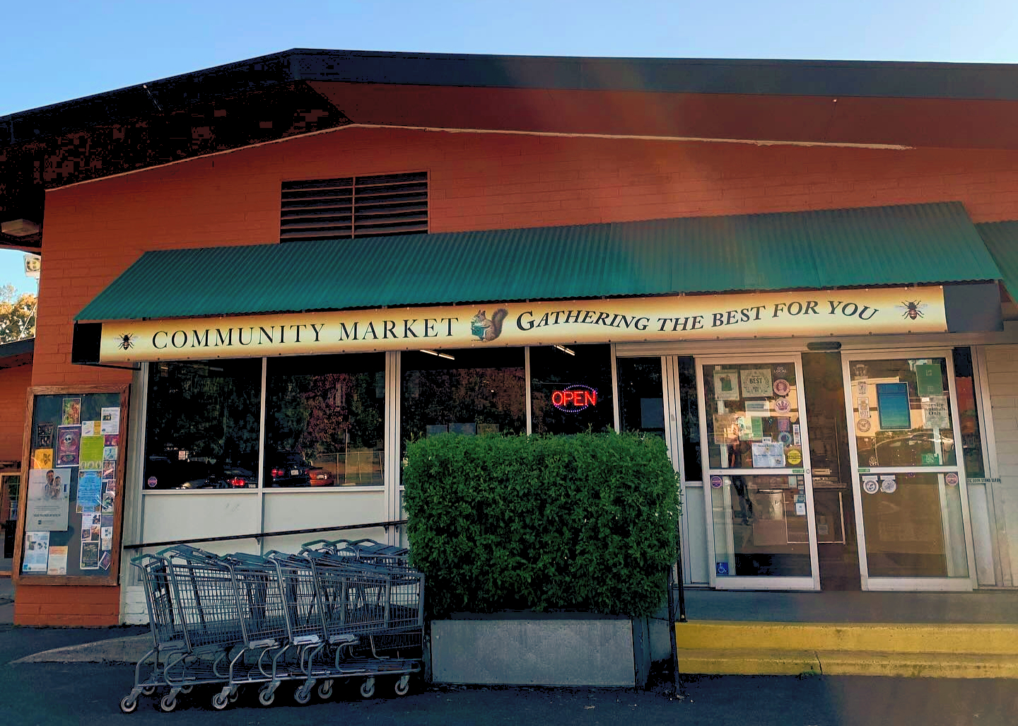 Santa Rosa Store Front. Orange building with green overhang with sign that says Community Market Gathering the Best for You.