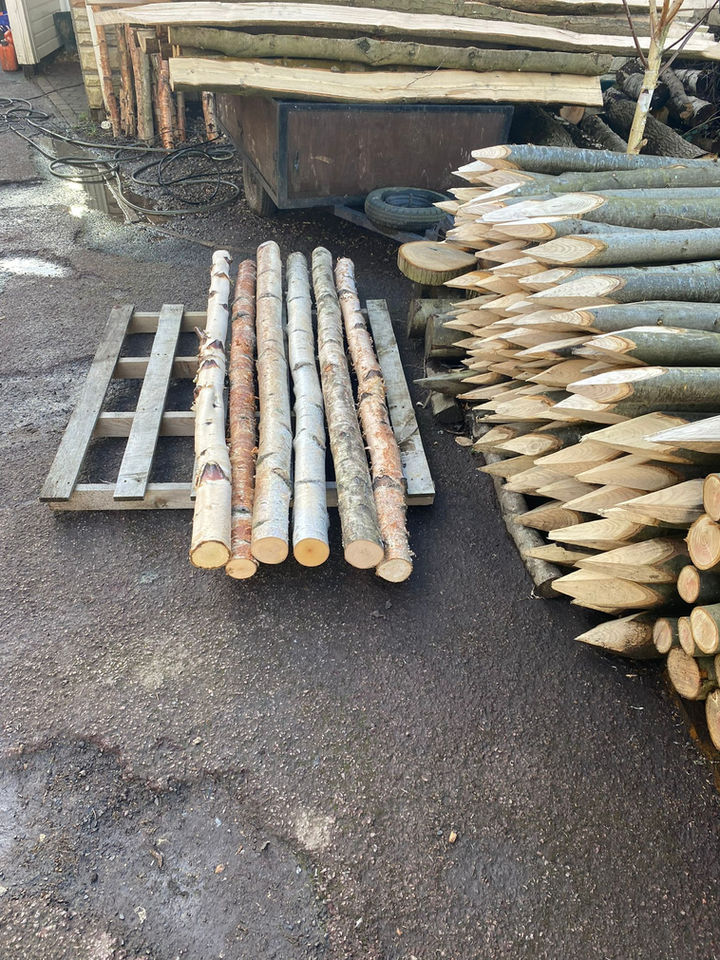 Wooden logs and fence posts stacked on concrete ground The Woodsman.