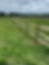 Wooden fence in a green field. Power lines in the background.