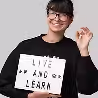 Yelyzaveta Moroz, brand marketing manager, smiling and holding a sign that says 'Live and Learn'