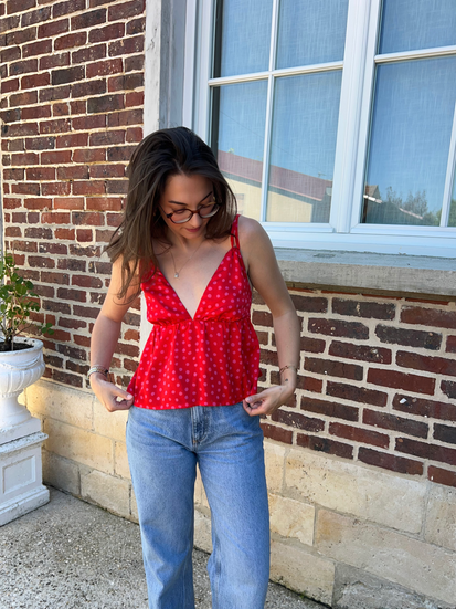 Femme brune portant un top cousu main dans un tissu rouge à pois rose.
