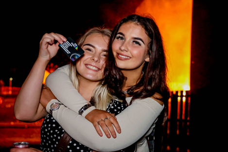 Two young women smiling and embracing at an event