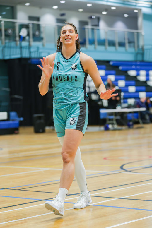Basketball player in light blue Phoenix uniform smiling