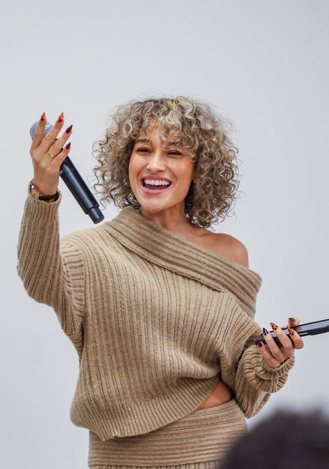 Smiling woman with curly hair, holding two microphones